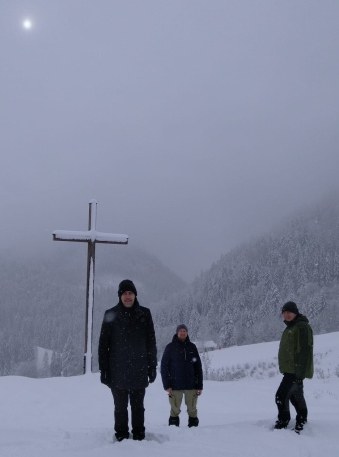Männer im Nebel vor einem Gipfelkreuz
